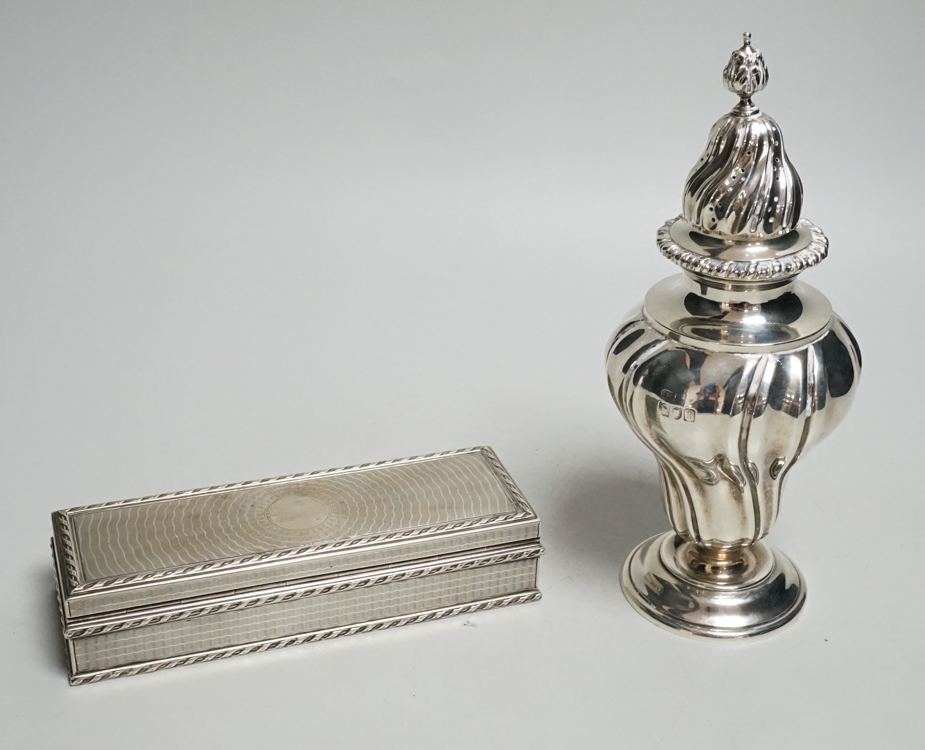 A George V engine turned rectangular silver box and cover by Goldsmiths & Silversmiths Co Ltd, London, 1911, 15.2cm and an Edwardian silver sugar caster, same maker, London, 1906, 15.5oz.